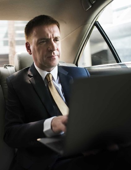 businessman inside a car working on his laptop